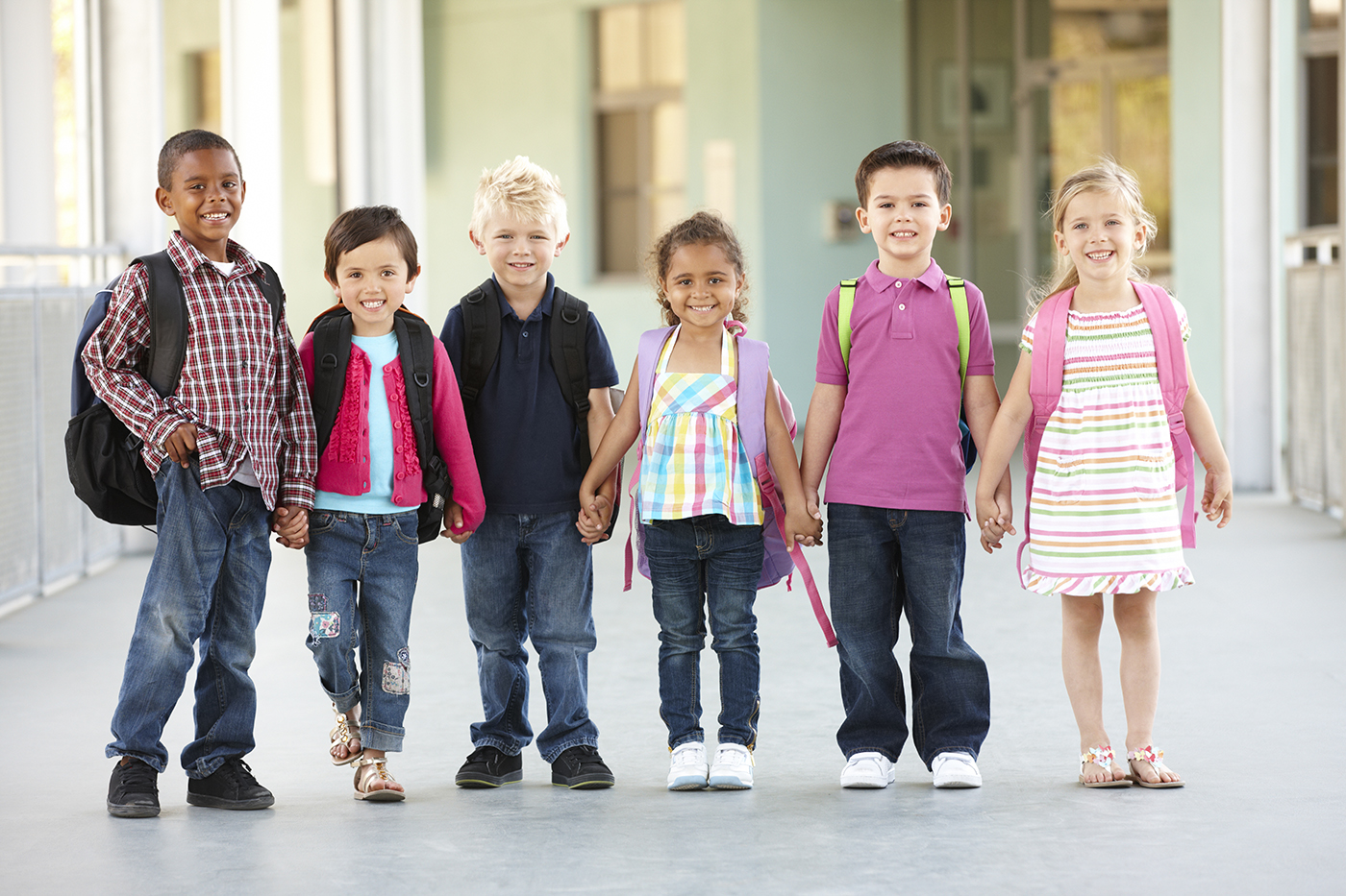 diverse children holding hands with backpacks