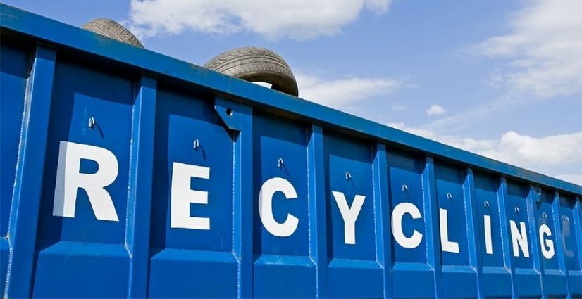 Tires in a blue recycling dumpster with the word RECYCLING written on it