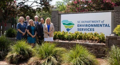 small group of people standing outside in front of SCDES sign