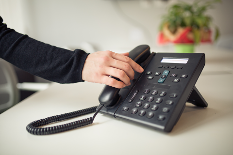 Desk table office phone and womans hand picking up