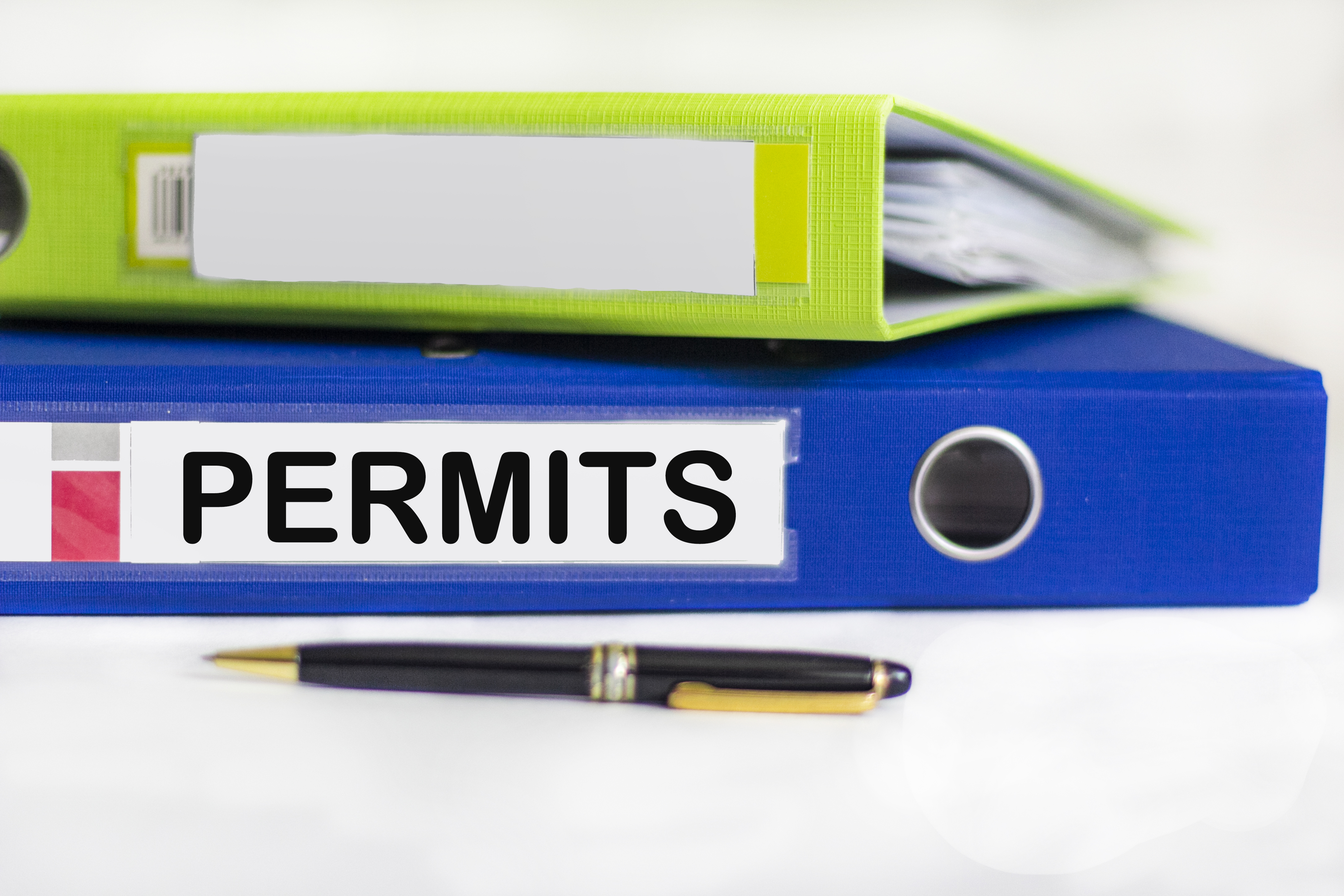 On the desktop are notebooks, a pen and a blue folder for papers with the inscription PERMIT